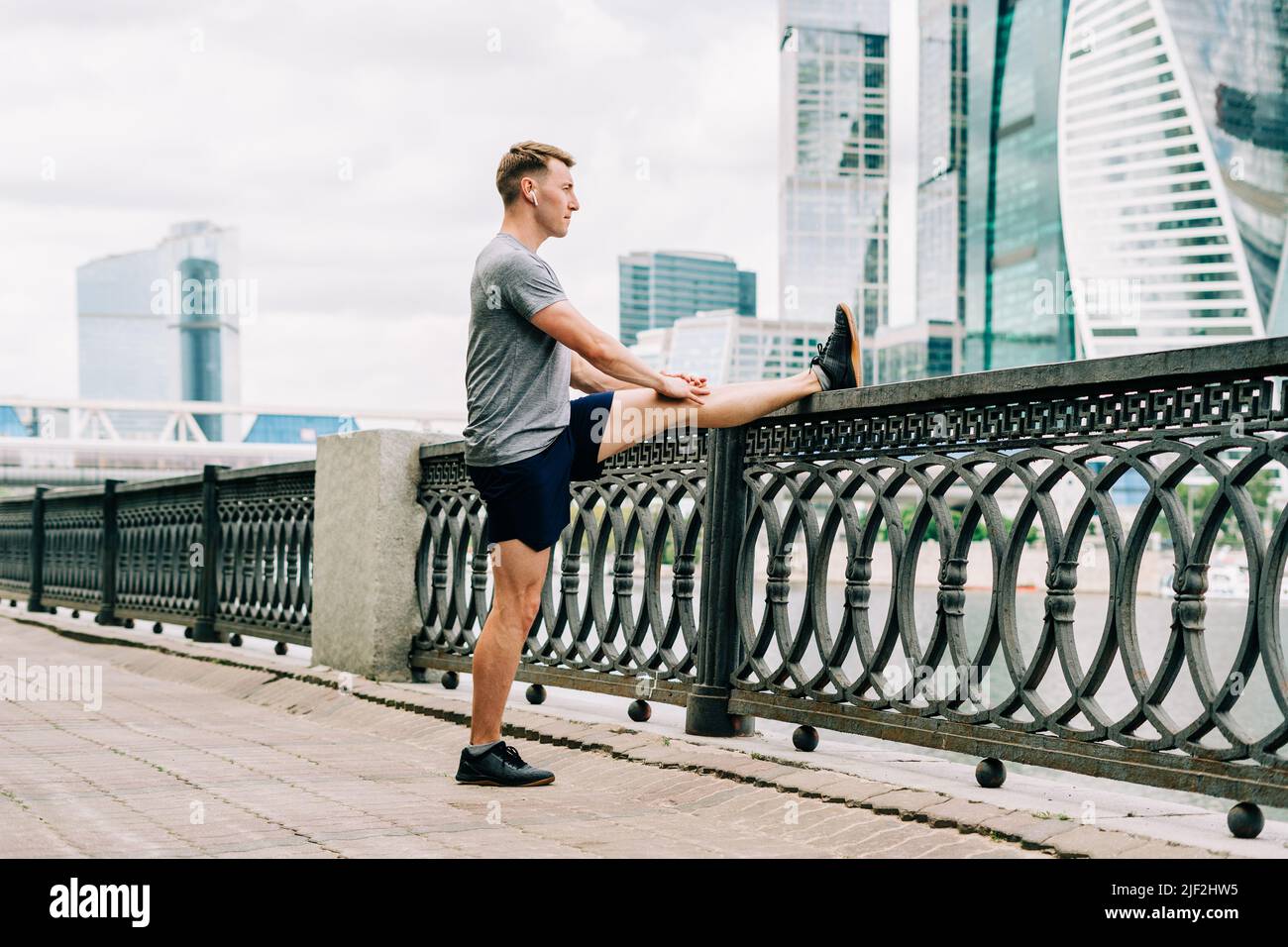 Young fitness man runner stretching legs before exercise run outdoors in city urban street. Healthy lifestyle and sport concept Stock Photo