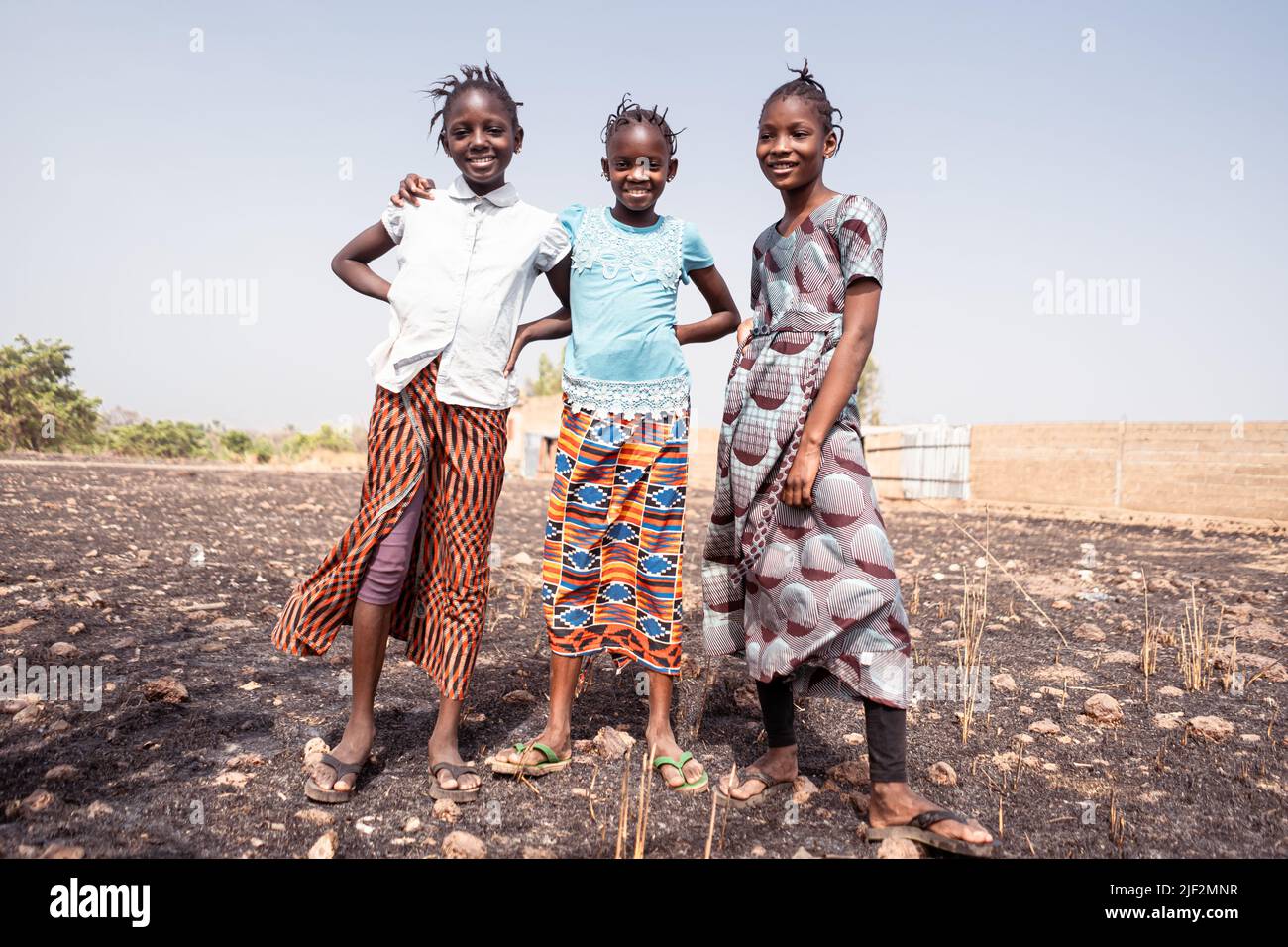 Three African girls standing together on the ashes of a burned field; negative impact of unsustainable farming practice Stock Photo