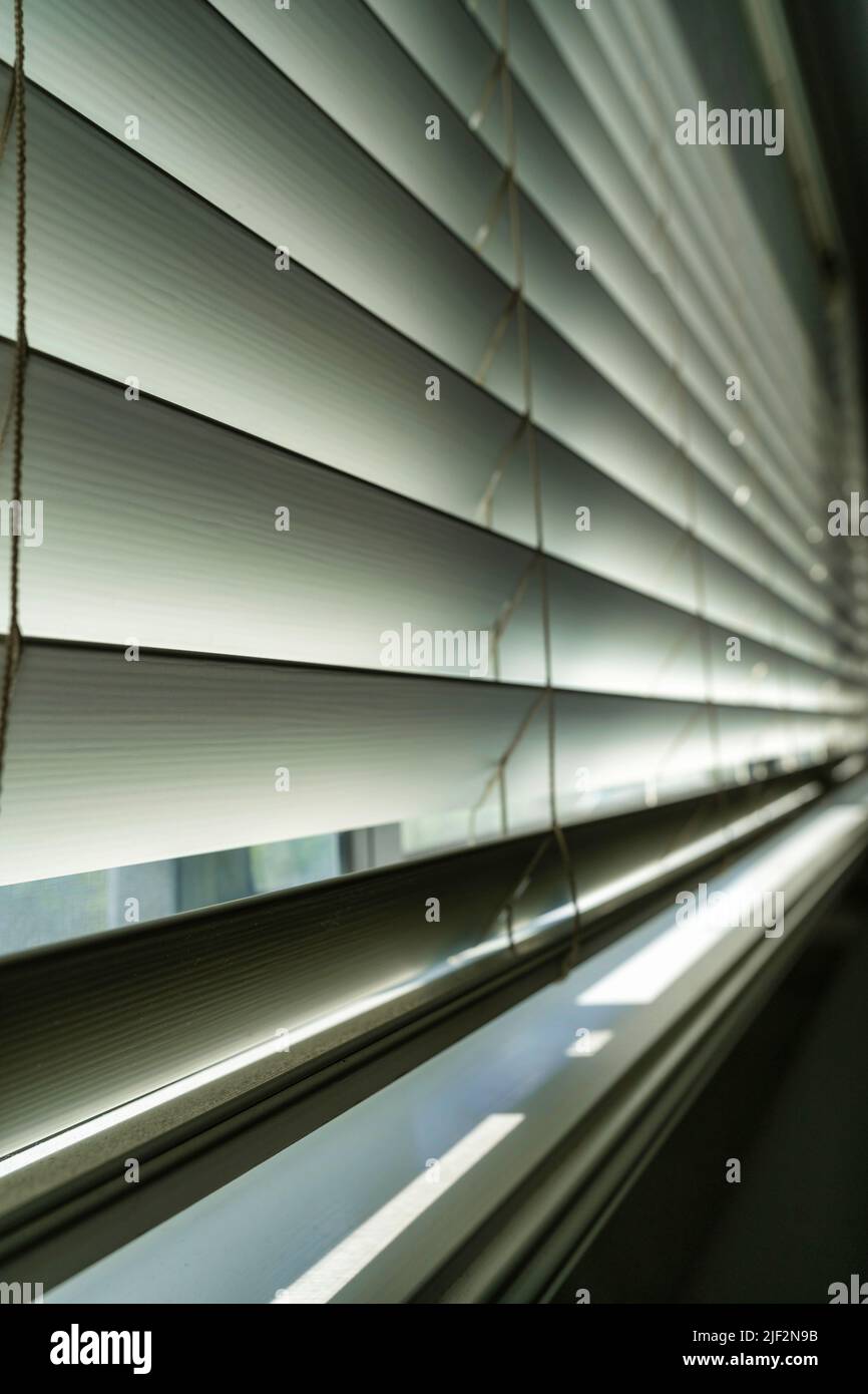 A vertical closeup of white blinds closing a window Stock Photo