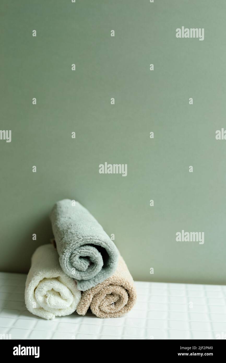 Bathroom towel on white table. khaki green wall background. skin care and spa concept Stock Photo