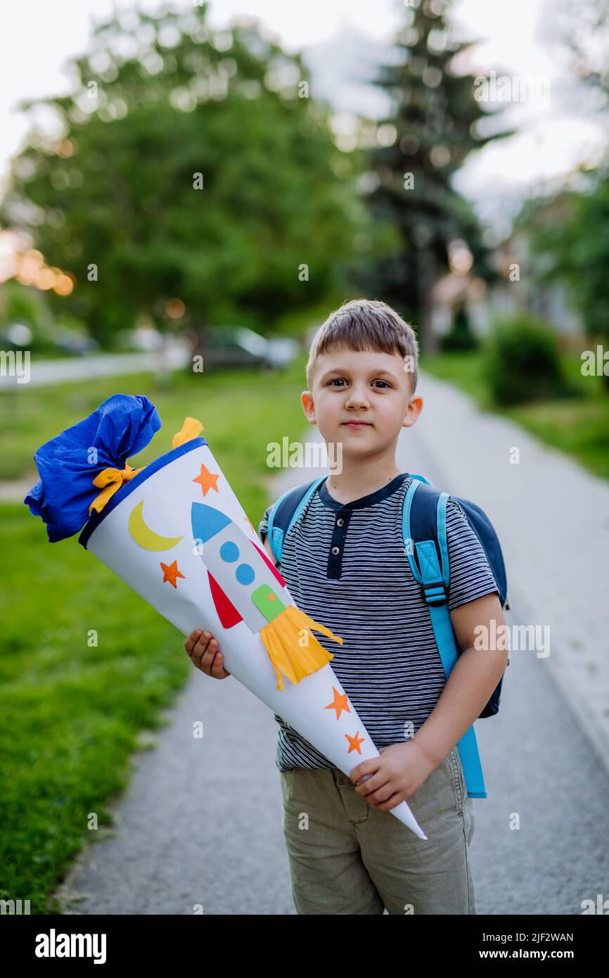 Little kid boy with school satchel on first day of school, holding school cone with gifts Stock Photo