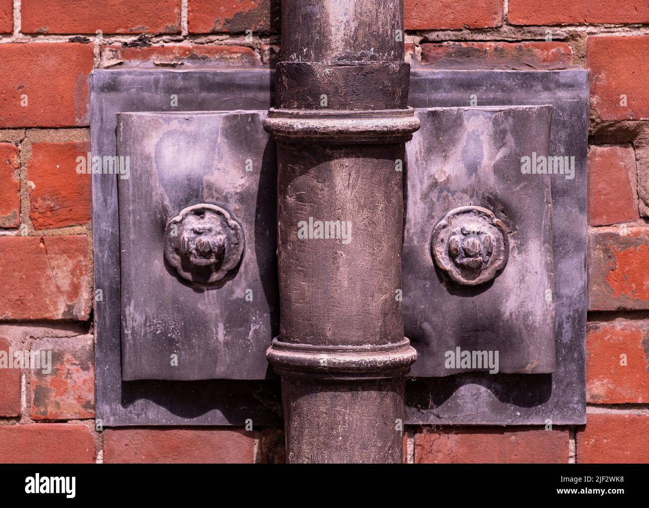 Ornate old fashioned lead down pipe and wall fixing for rain water Stock Photo