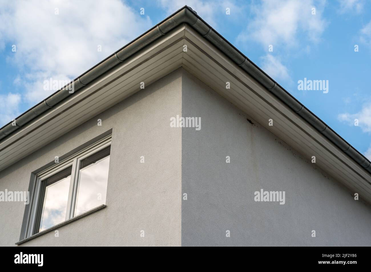 Upper floor of a white plastered house with roof box and double window Stock Photo