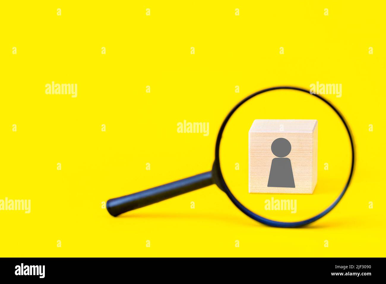 Search for talent or employee candidate, human resources concept, personal identification, hiring staff. Magnifying glass and a wooden cube with a hum Stock Photo