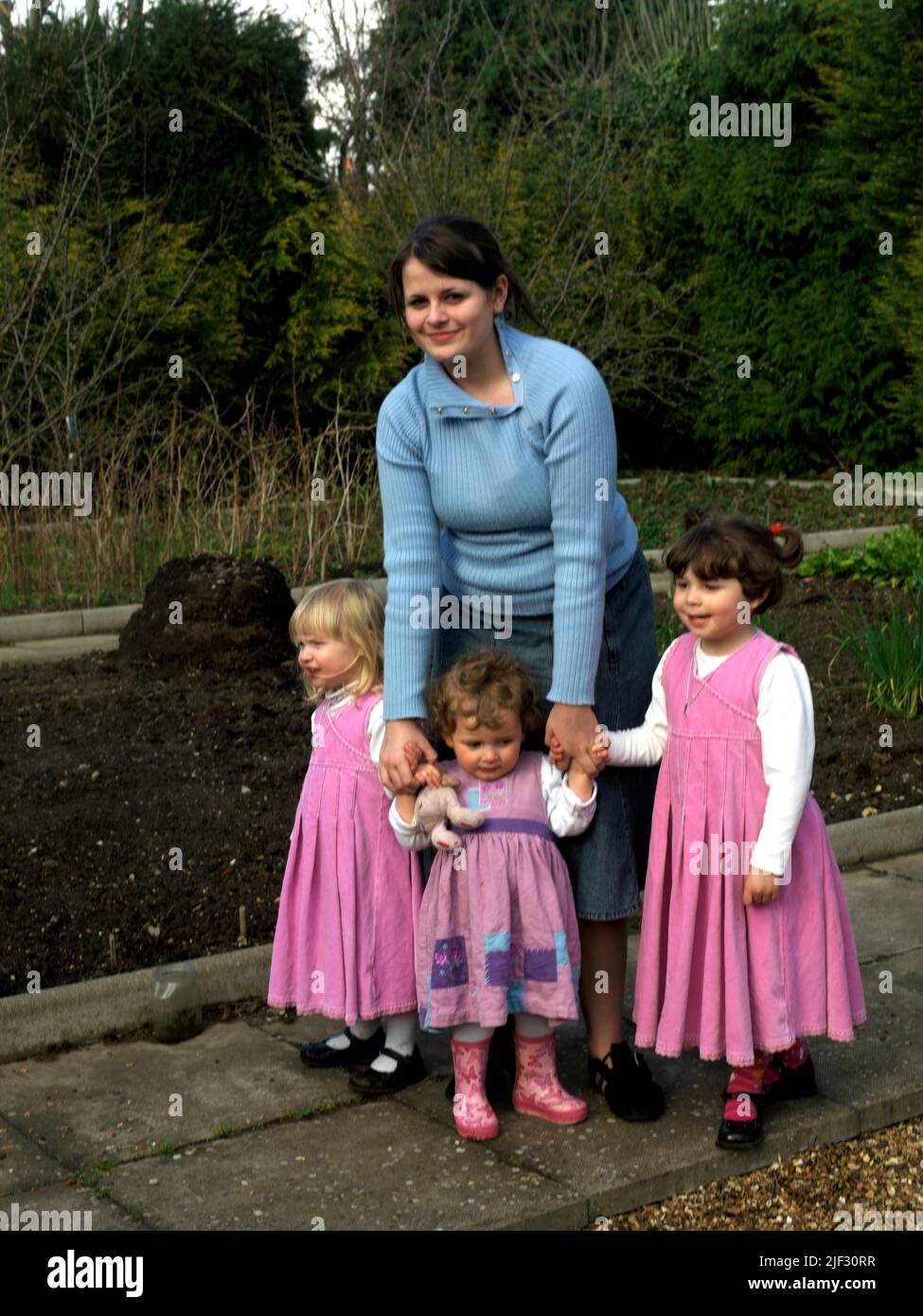 Fourteen Year old Girl Holding Hands with Her Nieces in Garden Surrey England Stock Photo