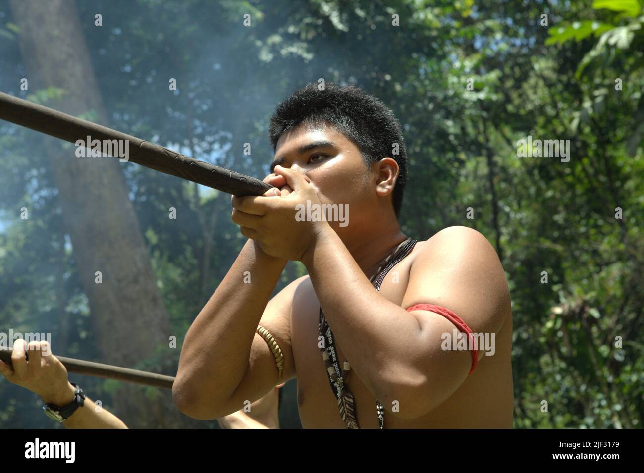 A tourism worker demonstrating an indigenous way of hunting with blowgun at Mari Mari Cultural Village, a village that is designed to showcase the cultures of five ethnic groups of Sabah—a Malaysian state in North Borneo, which is located on the outskirts of Kota Kinabalu in Sabah, Malaysia. Stock Photo