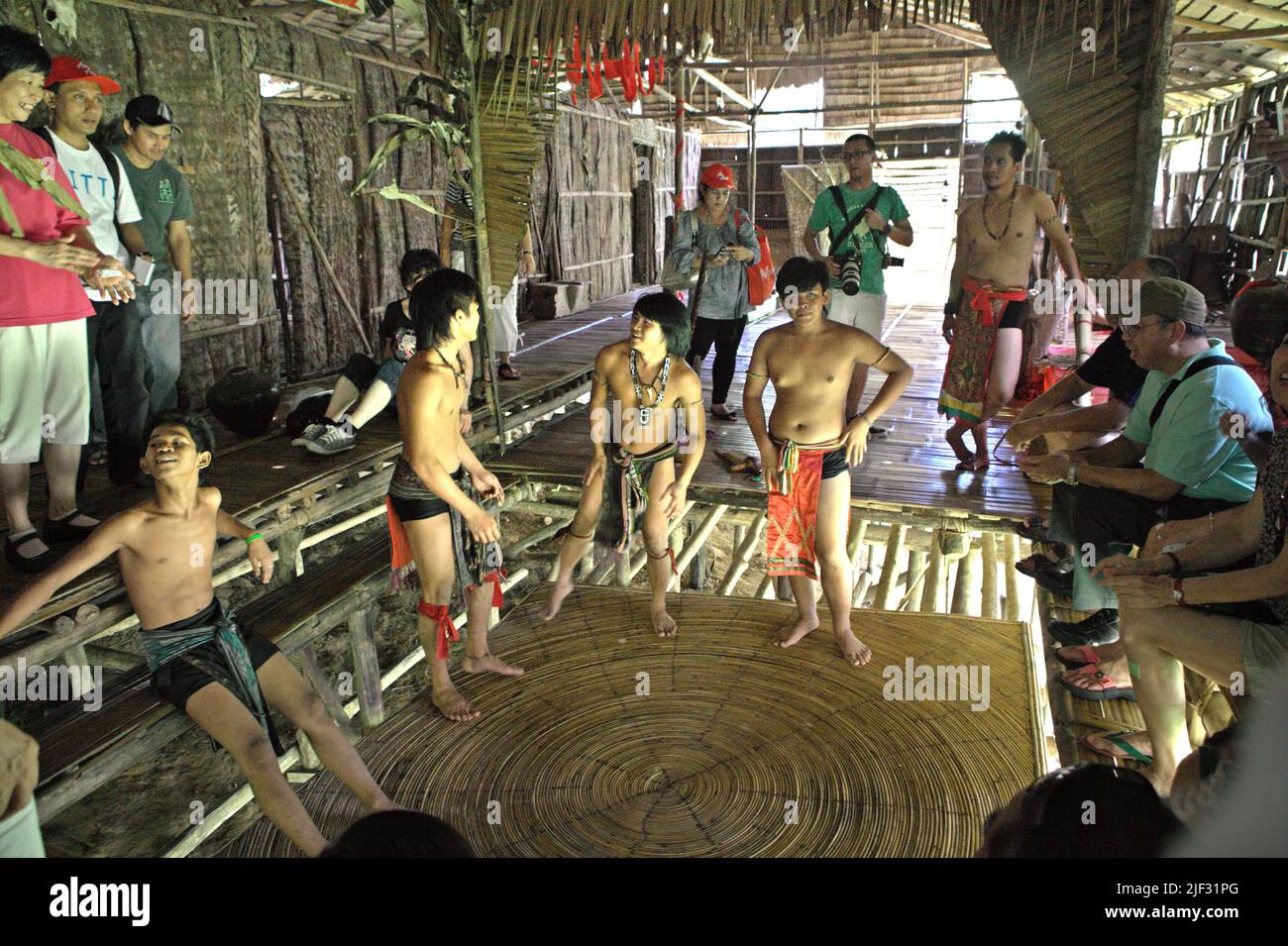 Tourism workers wearing indigenous attires showing a round trampoline made of rattan at Mari Mari Cultural Village, a village that is designed to showcase the cultures of five ethnic groups of Sabah—a Malaysian state in North Borneo, which is located on the outskirts of Kota Kinabalu in Sabah, Malaysia. Stock Photo