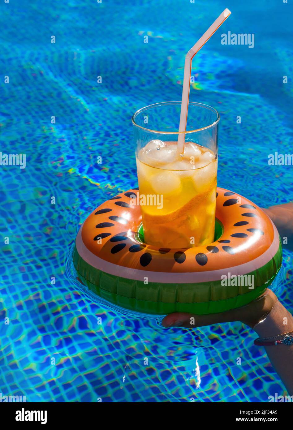 https://c8.alamy.com/comp/2JF34A9/cold-refreshing-drink-with-ice-and-a-straw-in-the-inflatable-ring-in-shape-of-watermelon-in-a-womans-hand-in-a-pool-of-blue-water-concept-of-summer-2JF34A9.jpg