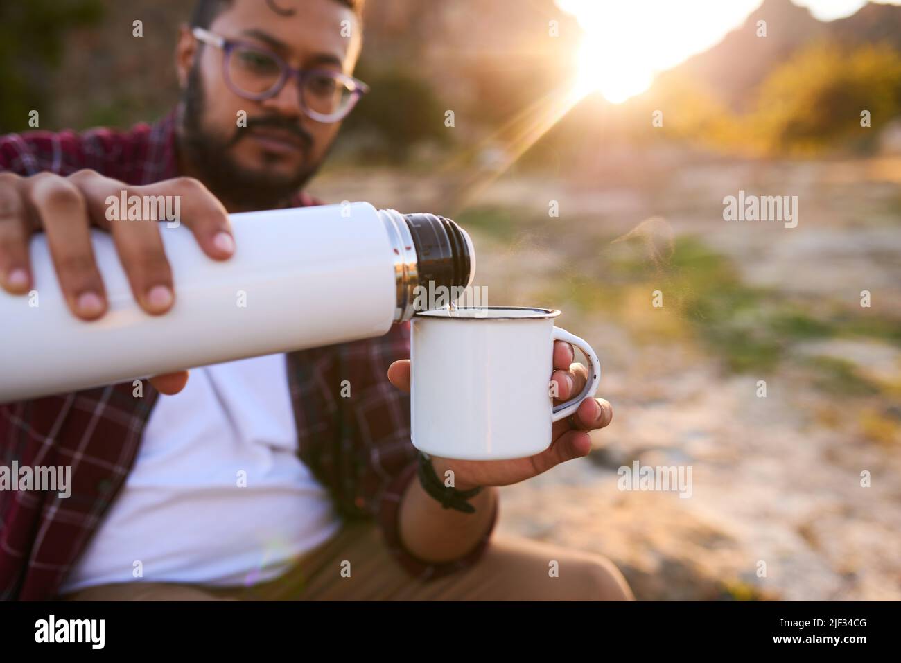 Close-up of Man Holding Thermos and an Iron Mug, Pouring Hot Tea