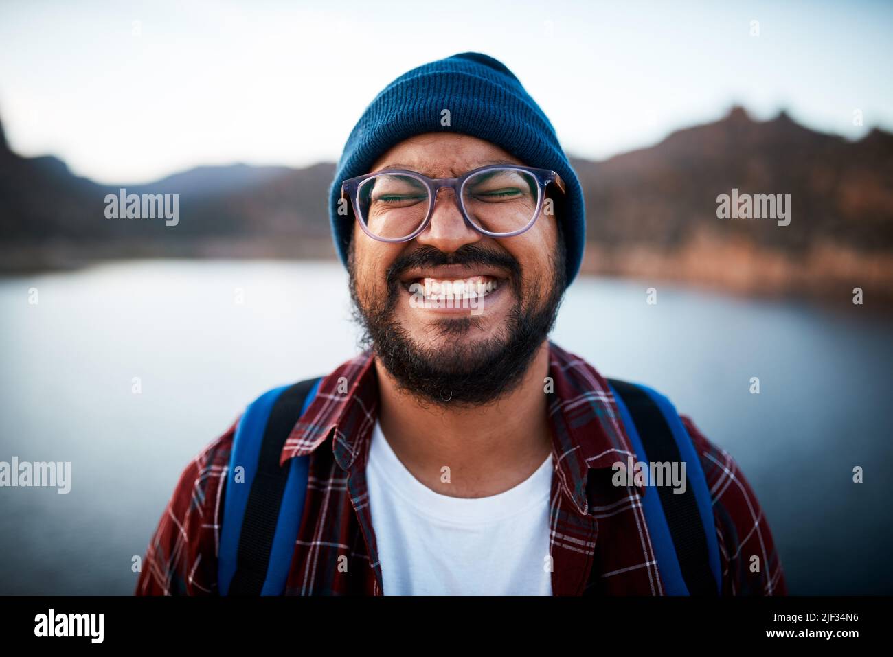 An attractive man pulls a silly grin on a hiking trip by a lake Stock Photo