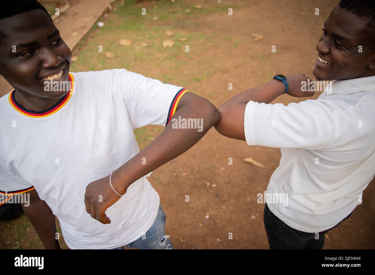 Two friends in africa greeting each other with elbows to reduce contact during coronavirus pandemic, new normal concept Stock Photo