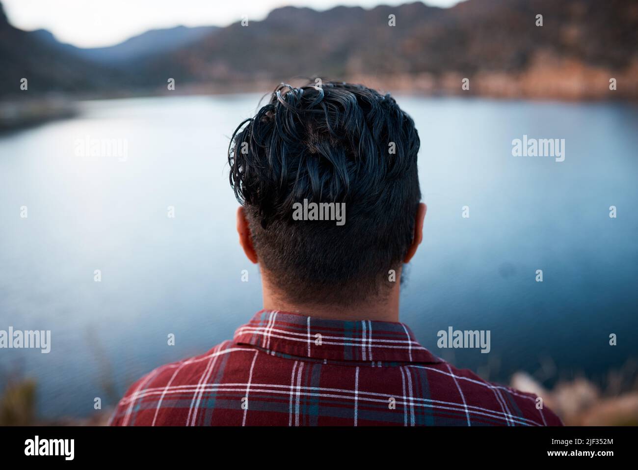 The back of a man's head while he admires the lake view on camping mountain trip Stock Photo