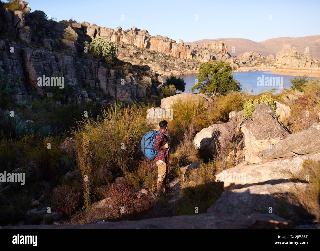 An unidentified man hikes in a wilderness with lake view, backpack adventure Stock Photo
