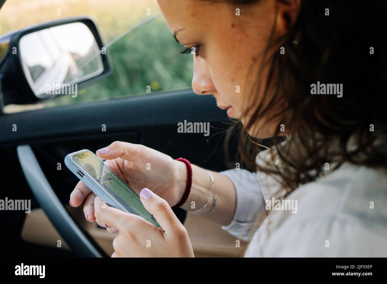 Young woman looking at her phone in the car Stock Photo