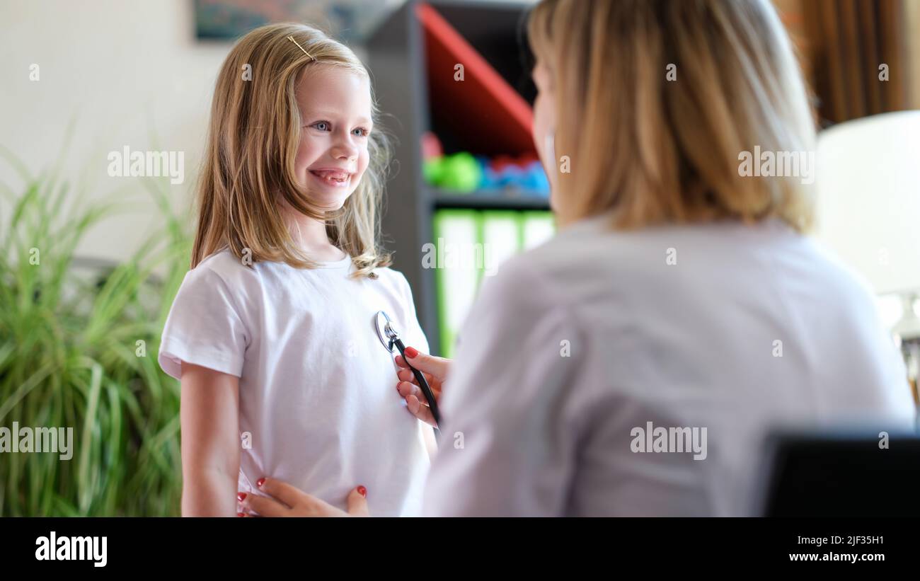 Pediatrician listens to lungs of little girl child with stethoscope