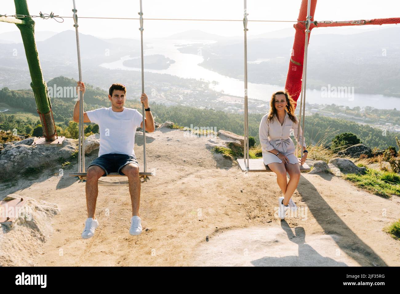 Young couple on a swing against a beautiful landscape in Galicia, Spain Stock Photo