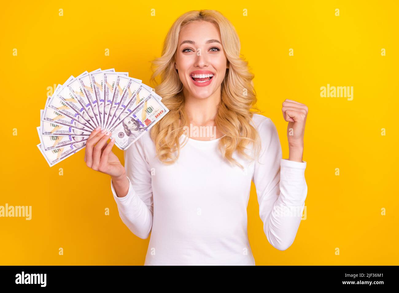 Photo of funny lucky woman wear white shirt rising fist money fan isolated yellow color background Stock Photo