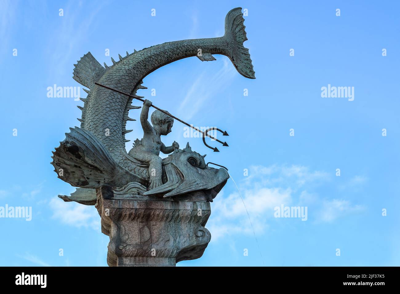Triton fountain part in the city of Duisburg, Germany, son of Poseidon with a trident sitting on a big fish against a blue sky with copy space Stock Photo