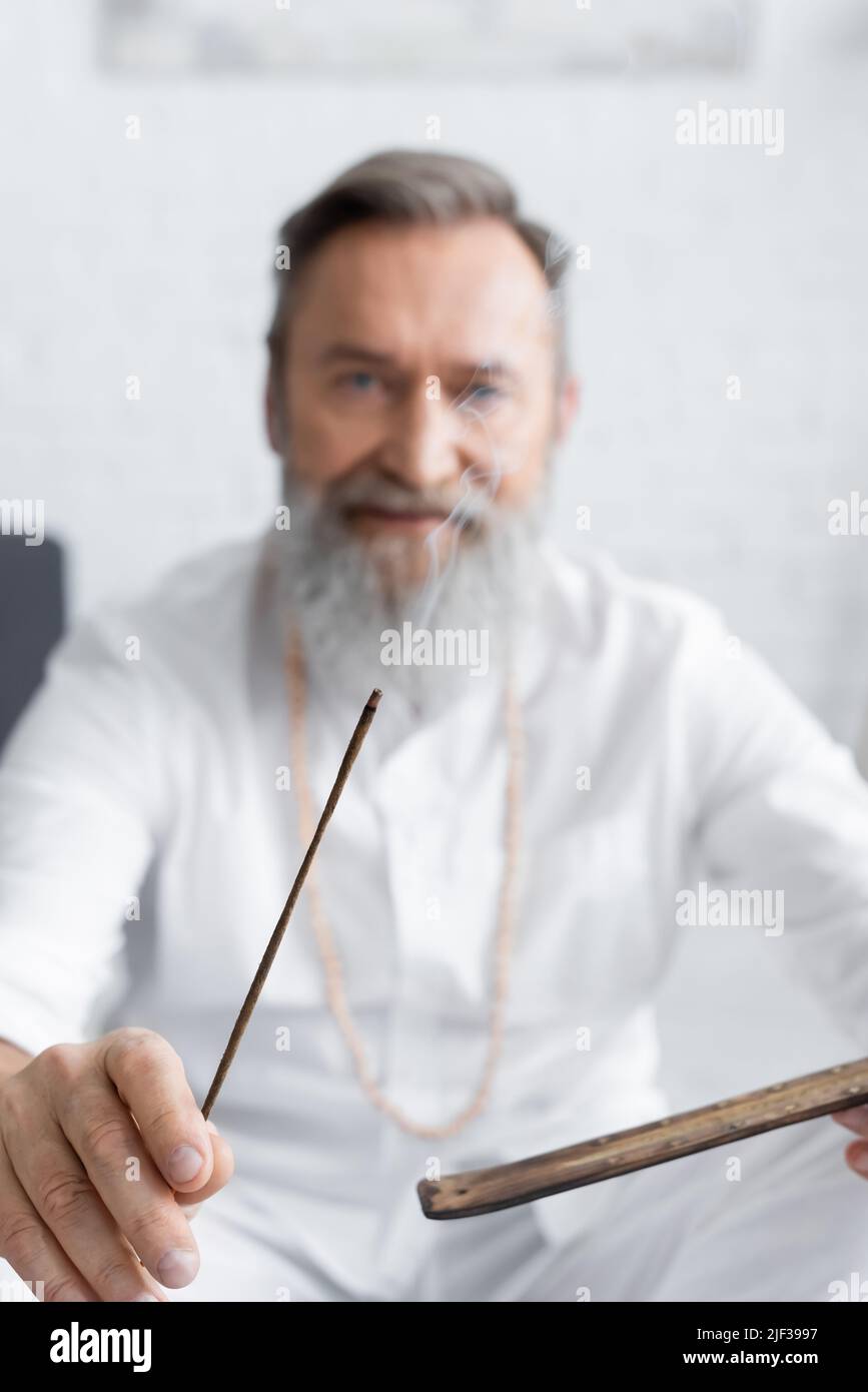 blurred ayurvedic guru holding smoldering aroma stick at home Stock