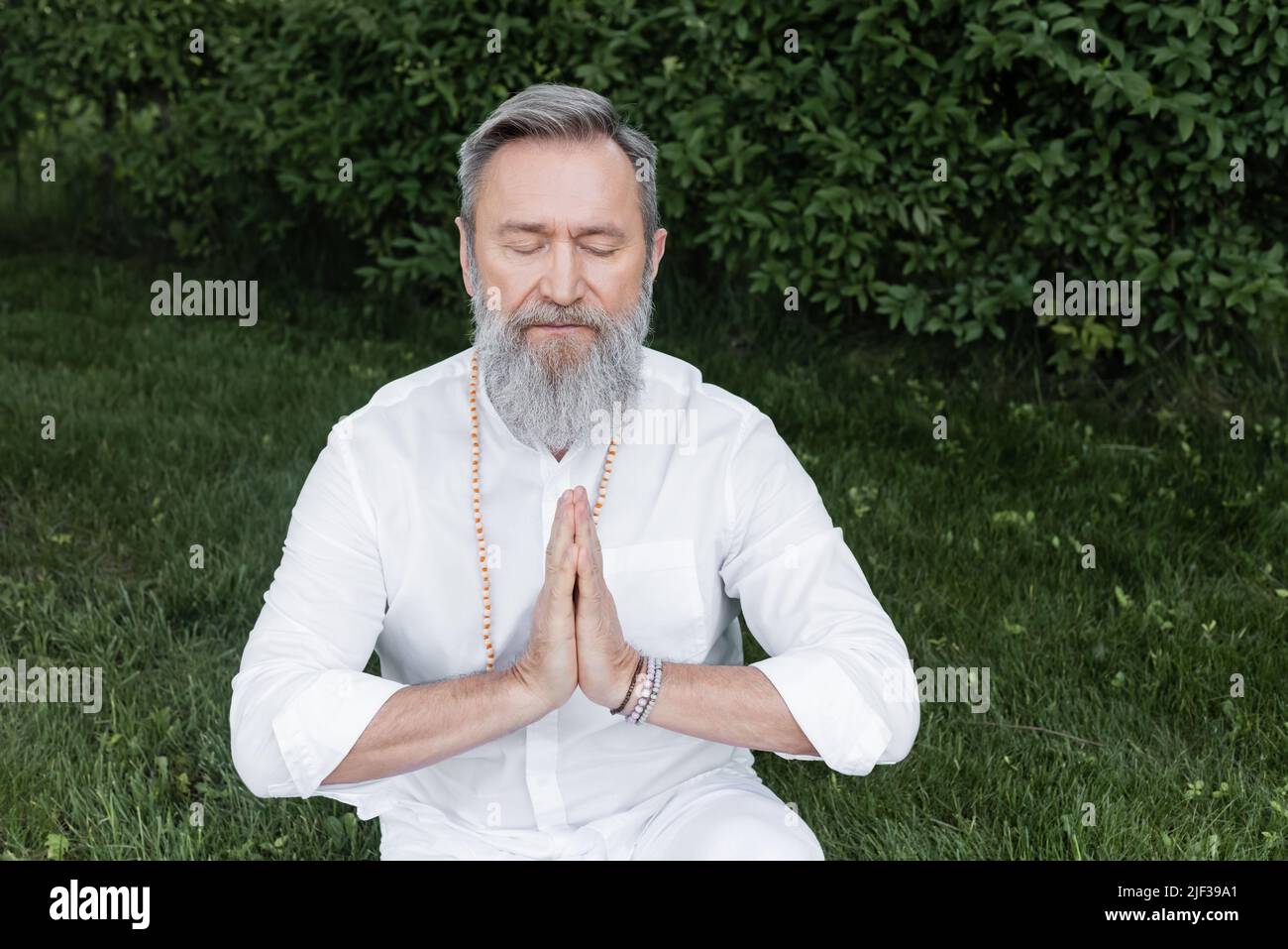 senior master guru meditating with closed eyes and praying hands in ...