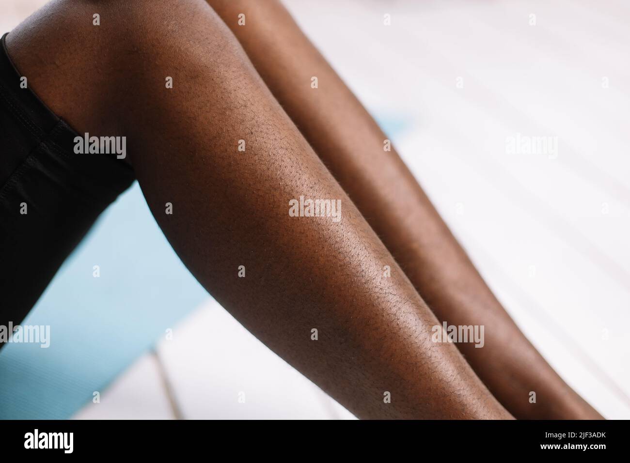Bare legs of afro american woman closeup, blurred background free copy space. Black person lying with bent legs. Hairy and unshaven legs, new normal Stock Photo