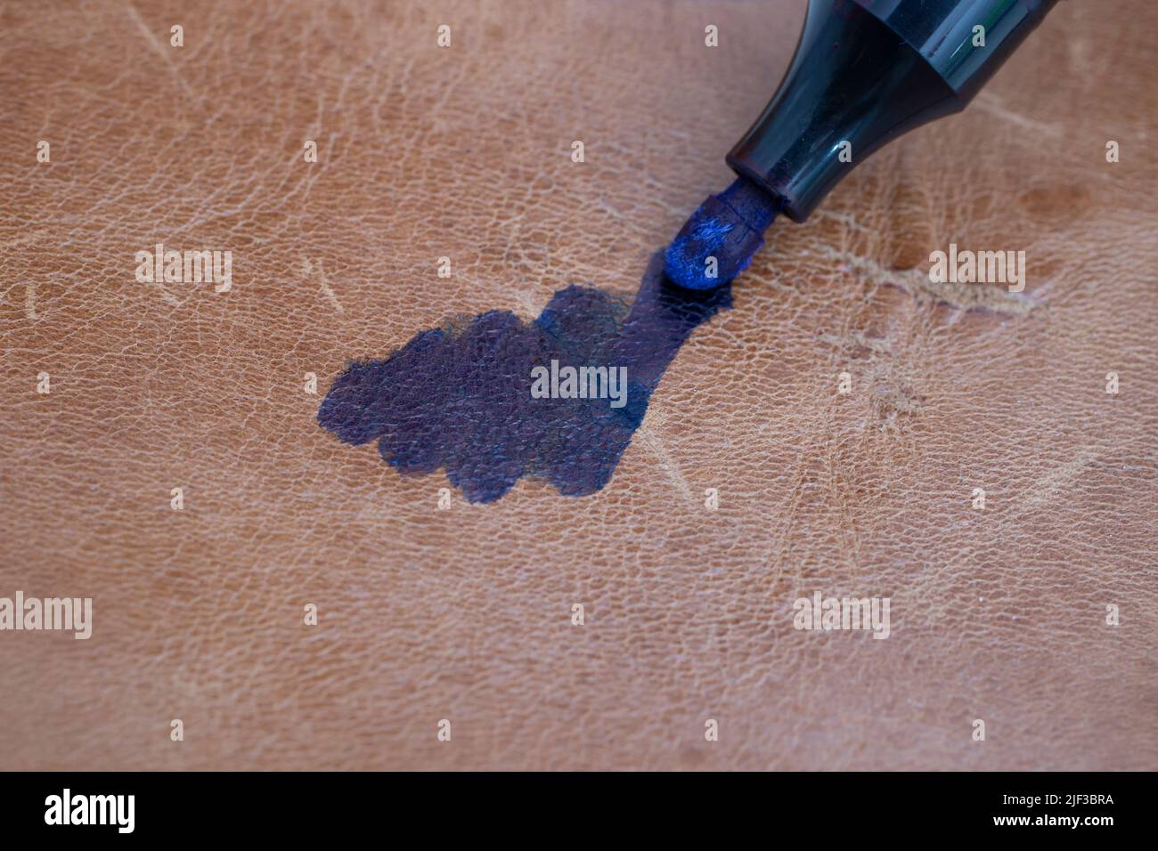 Permanent blue marker scribbling on brown leather, blurred soft focus