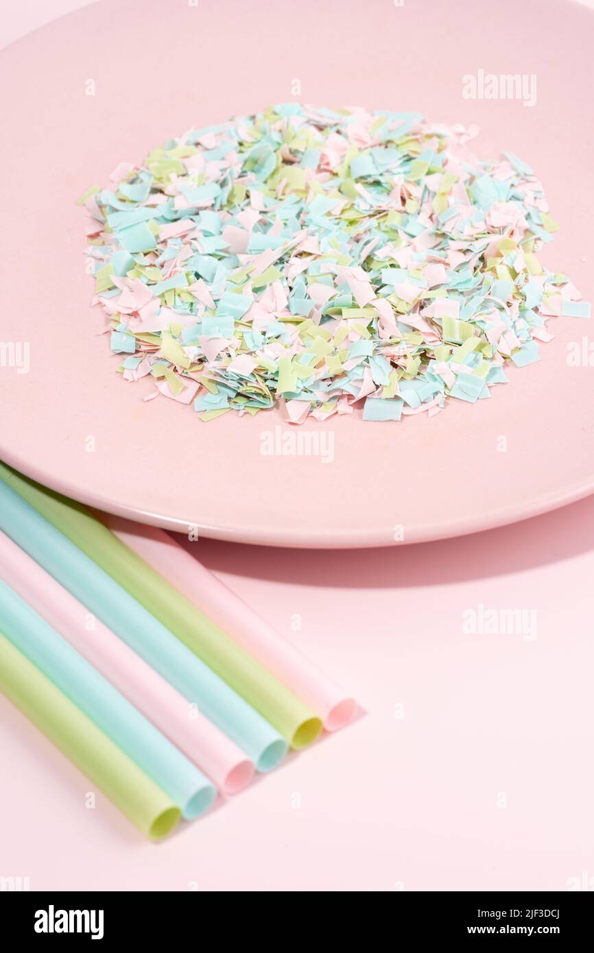 Drinking straws and plate full of microplastics on a pink background. Impact of micro plastic on the food chain. The idea of micro plastic pollution. Stock Photo