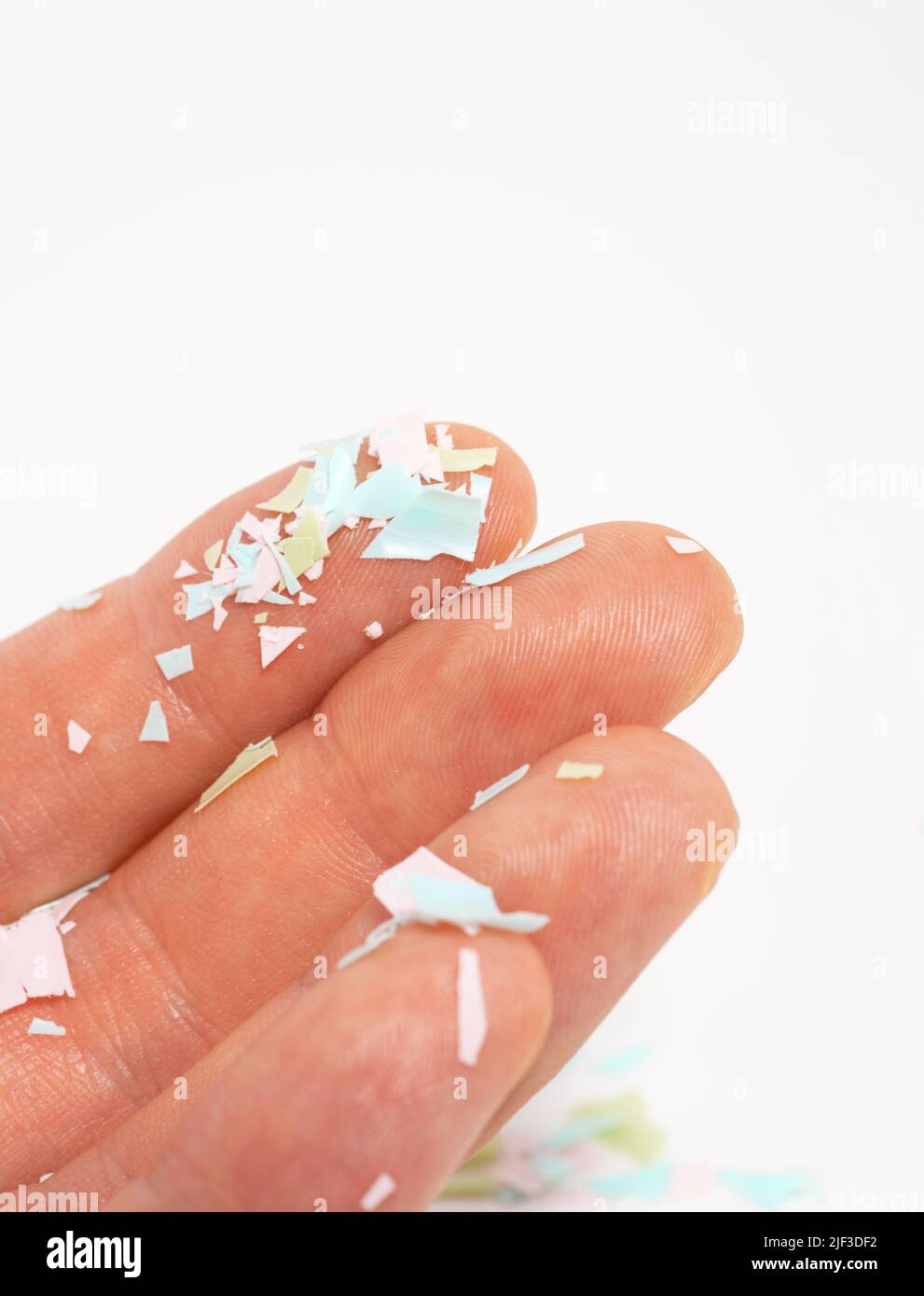 A close-up photo of microplastics lay on human hand. The idea of environmental damage. Concept of water pollution and global warming. White background Stock Photo