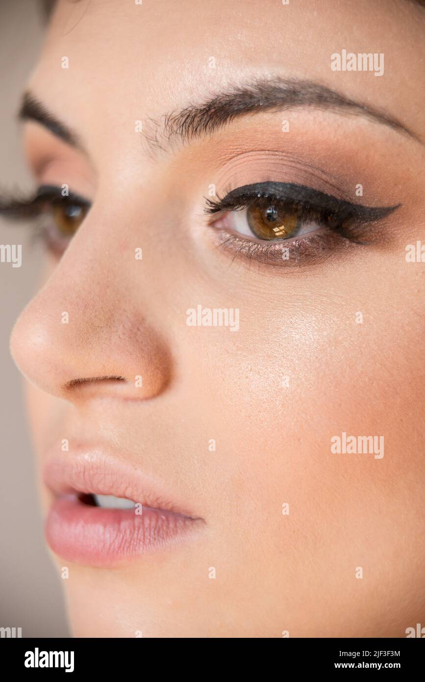 Macro detail of Caucasian model face with brown almond eyes during make-up session.  The model has white, clean complexion and black eye liner. Stock Photo
