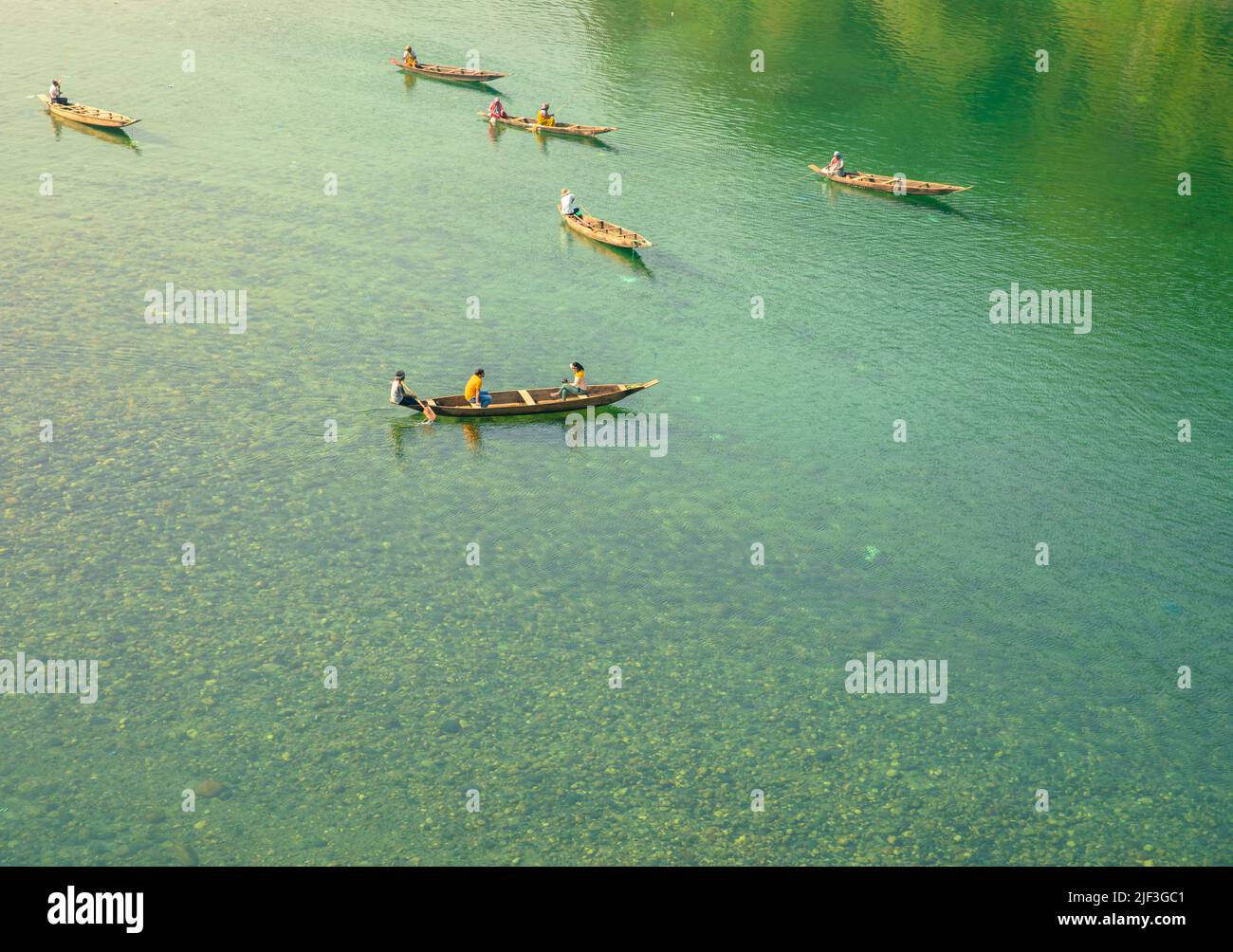 A group of people in wooden boats riding in a clear green lake Stock ...