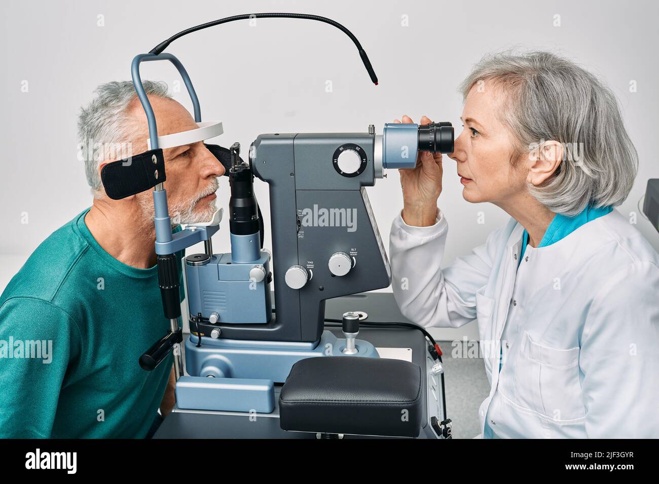 Optometrist doing sight test for senior man at modern ophthalmology clinic. Eye exam and vision diagnostic Stock Photo