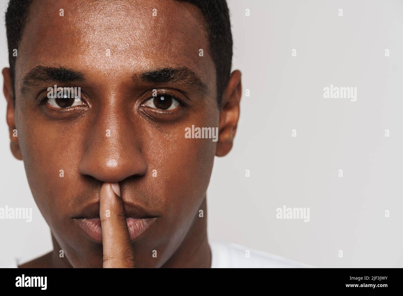 Black man showing silence gesture hi-res stock photography and 