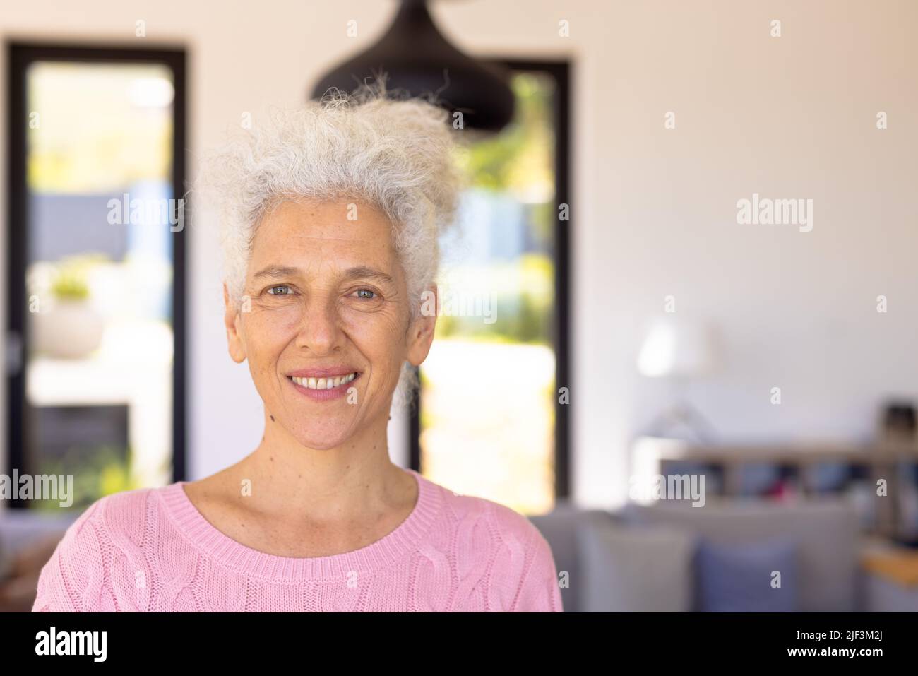 Close-up portrait of smiling caucasian senior woman against white wall in nursing home, copy space Stock Photo