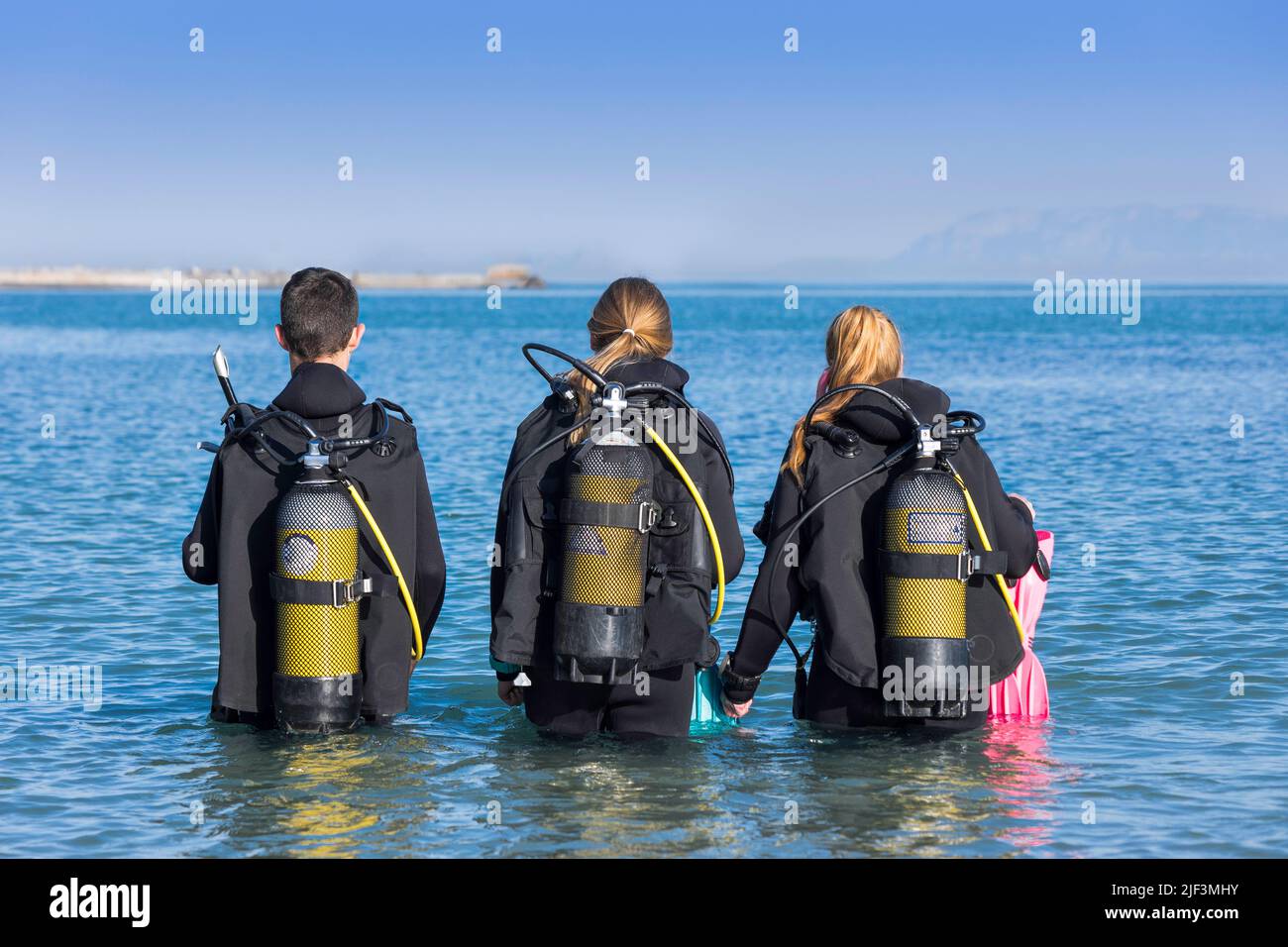 Scuba divers walking into the sea on a shore dive from behind Stock Photo