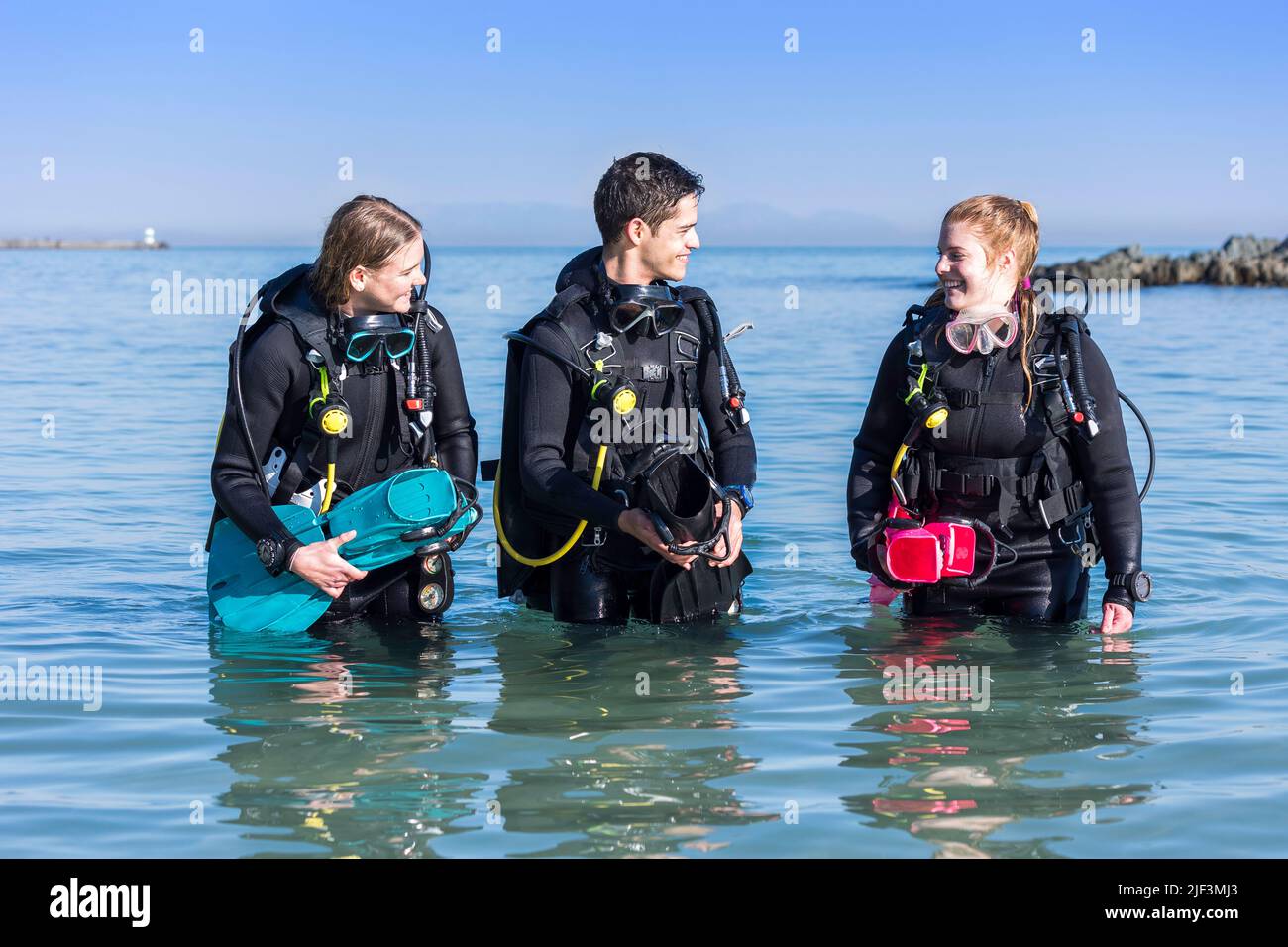Happy scuba divers walking out of the sea after a shore dive Stock Photo