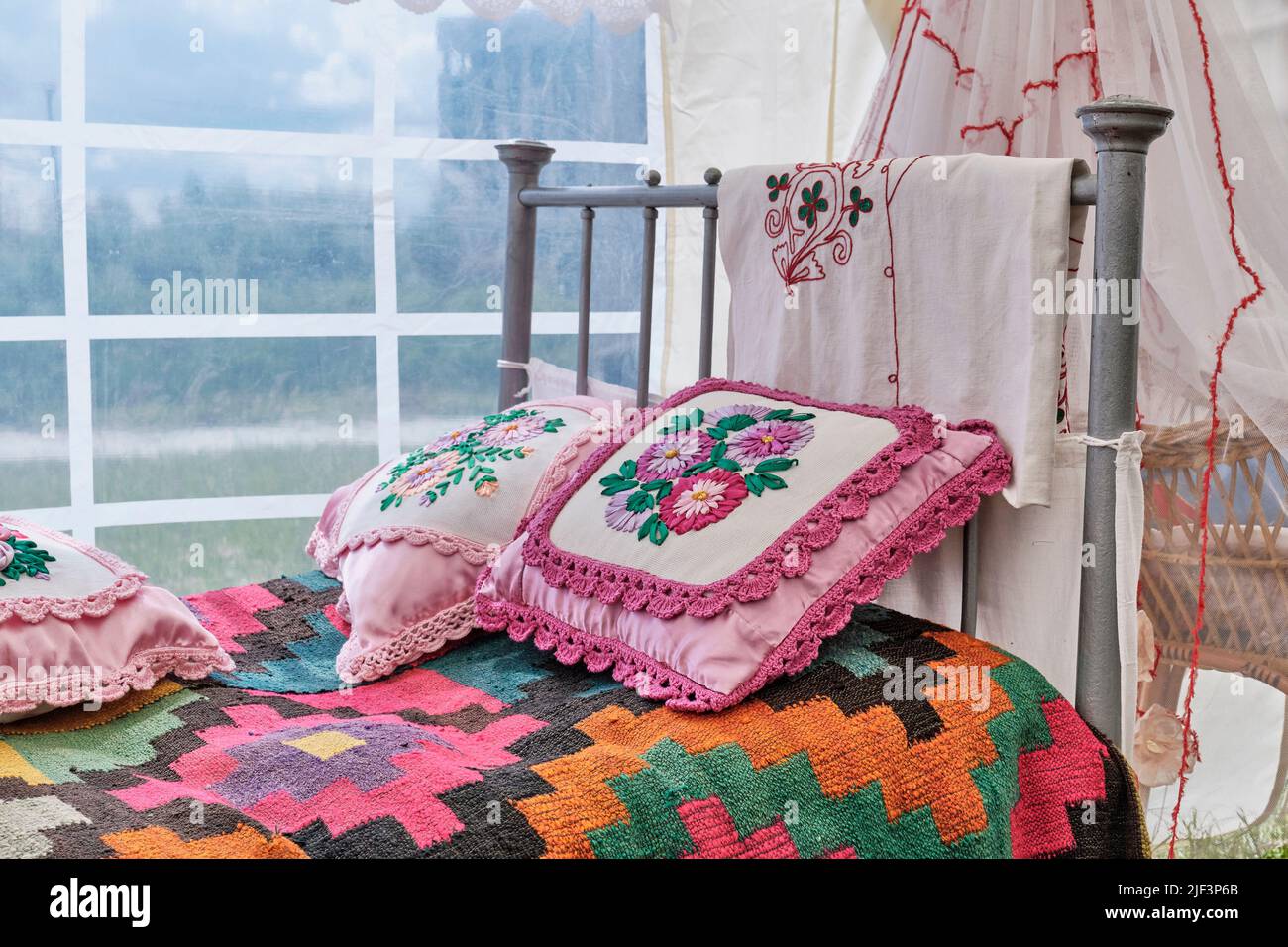 Traditional decor of bed in Tatar vintage style. Woven bedspread, pillows embroidered with ribbons Stock Photo