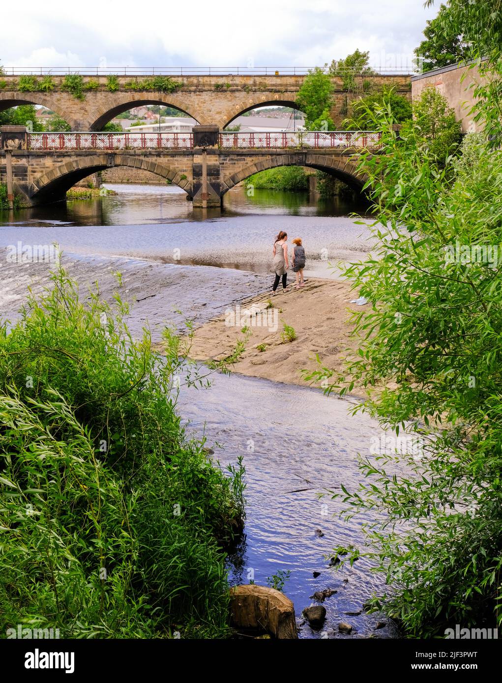 Sheffield, South Yorkshire, UK. June 11 2022. 2 girls are venturing into the river Don, close to the 5 weirs walk Stock Photo