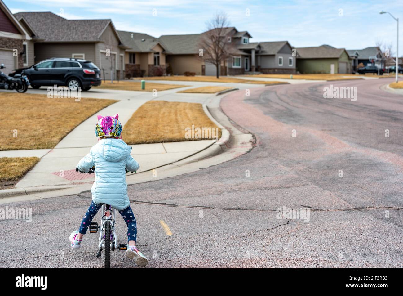 Young girl riding a bike safely across the road to a sidewalk while