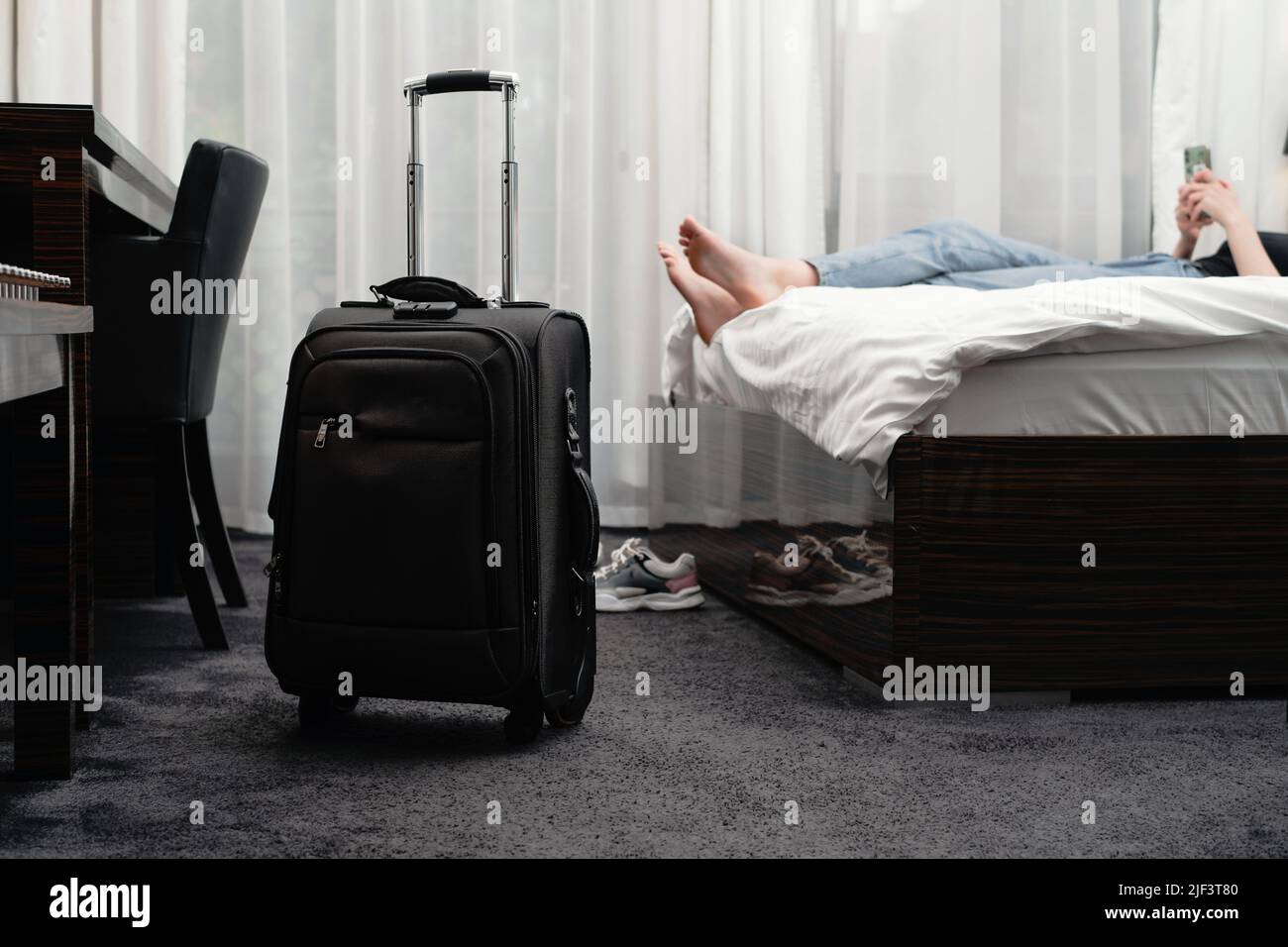 Woman Taking Off Footwear In A Hotel Room On The Bed. Tourist Relaxing 