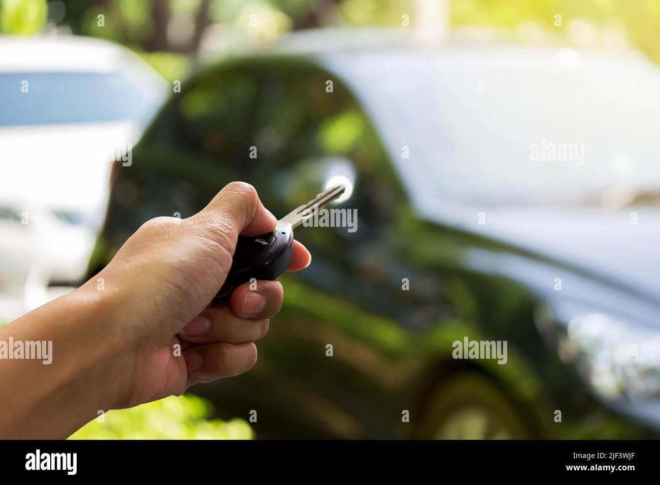 Close up hand holding the keys over blurred of used car for open the ...