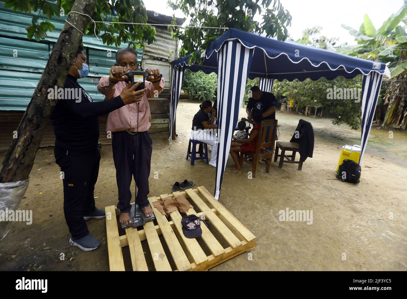 Valencia, Carabobo, Venezuela. 25th June, 2022. Junio 25, 2022. Un anciano es evaludo por un medico nutricionista miembro de la asociacion sin fines de lucro y con actividades netamente humanitarias ''Dar mas que recibir'' quienes celebraron su octavo aniversario con un operativo donde, donaron ropa, juguetes, las tradicionales arepas y el sancocho comunitario. También frcieron servicio de peluqueria, servicio medico de pediatria, odontologia, ginecologia, nutriciÃ³n, hematologia, y actividades recreativas para los niÃ±os, quienes al final cantaron cumpleaÃ±os y comieron torta. junto a mie Stock Photo