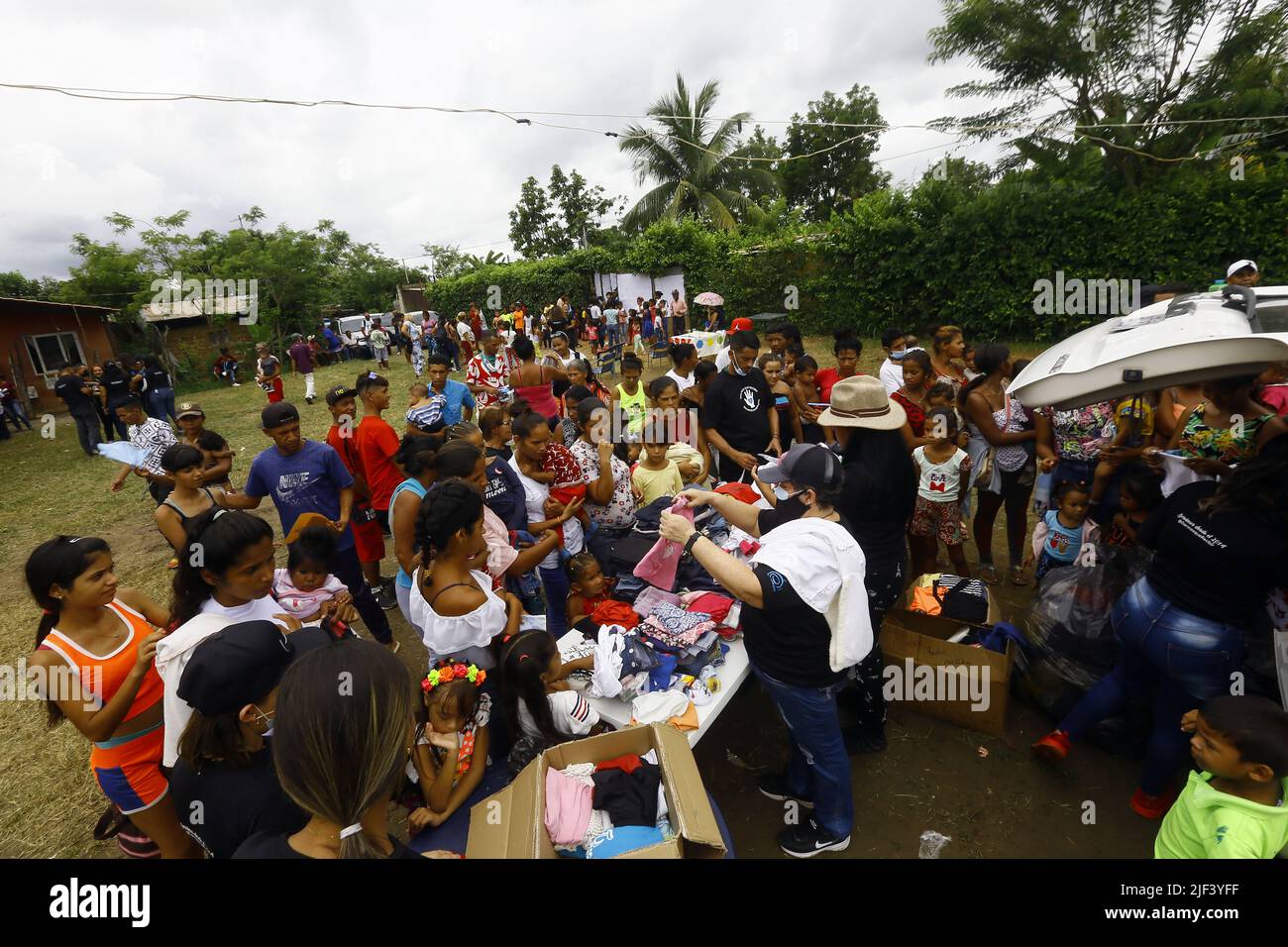 Valencia, Carabobo, Venezuela. 25th June, 2022. Junio 25, 2022. Entrega de ropas a residentes del sector La Yaguara, por miembros de la asociacion sin fines de lucro y con actividades netamente humanitarias ''Dar mas que recibir'' quienes celebraron su octavo aniversario con un operativo donde, donaron ropa, juguetes, las tradicionales arepas y el sancocho comunitario. También frcieron servicio de peluqueria, servicio medico de pediatria, odontologia, ginecologia, nutriciÃ³n, hematologia, y actividades recreativas para los niÃ±os, quienes al final cantaron cumpleaÃ±os y comieron torta. junt Stock Photo