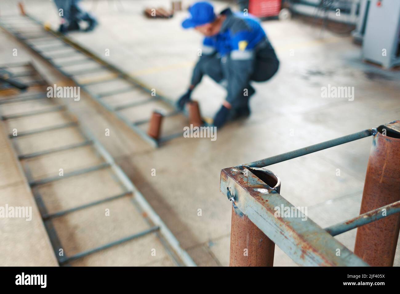 Workers in overalls make metal structures in workshop. Industrial background. Selective focus. Work in production. Real scene. Stock Photo