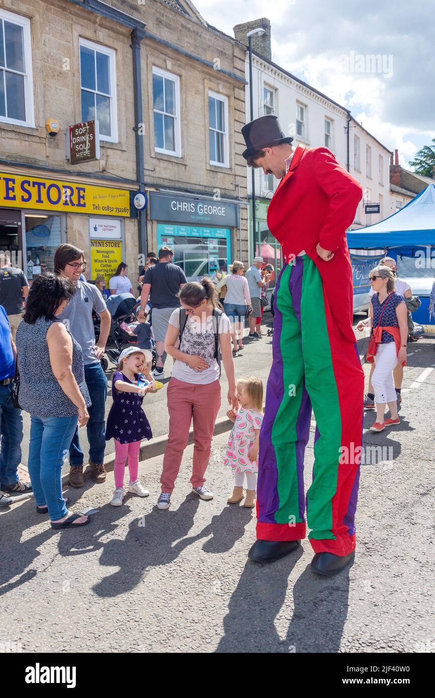 Entertainer on stilts with children at Circus Chater Fair, High Street, Thrapston