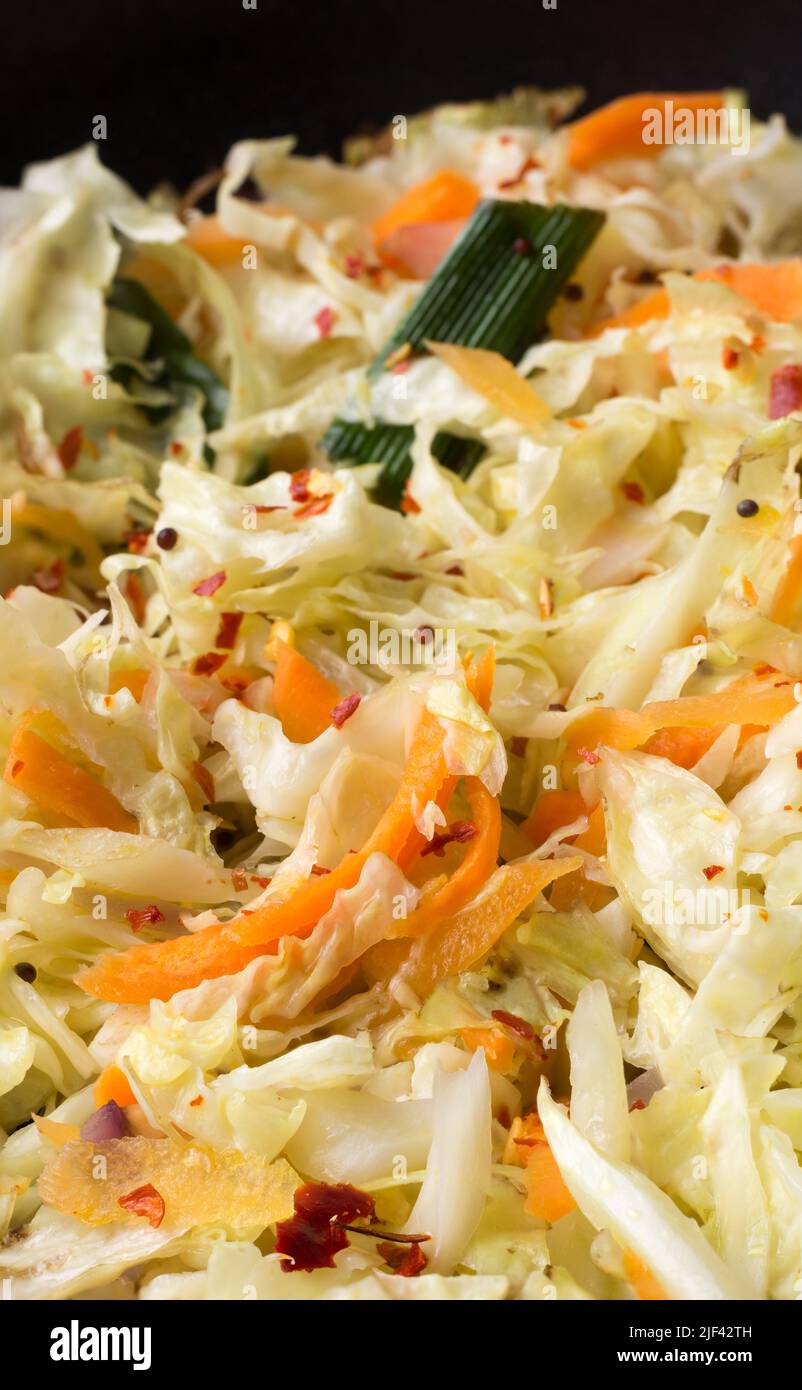 fresh healthy vegetable salad, cabbage and carrot mixed with olive oil and herbs, sprinkled mustard seeds, closeup view Stock Photo