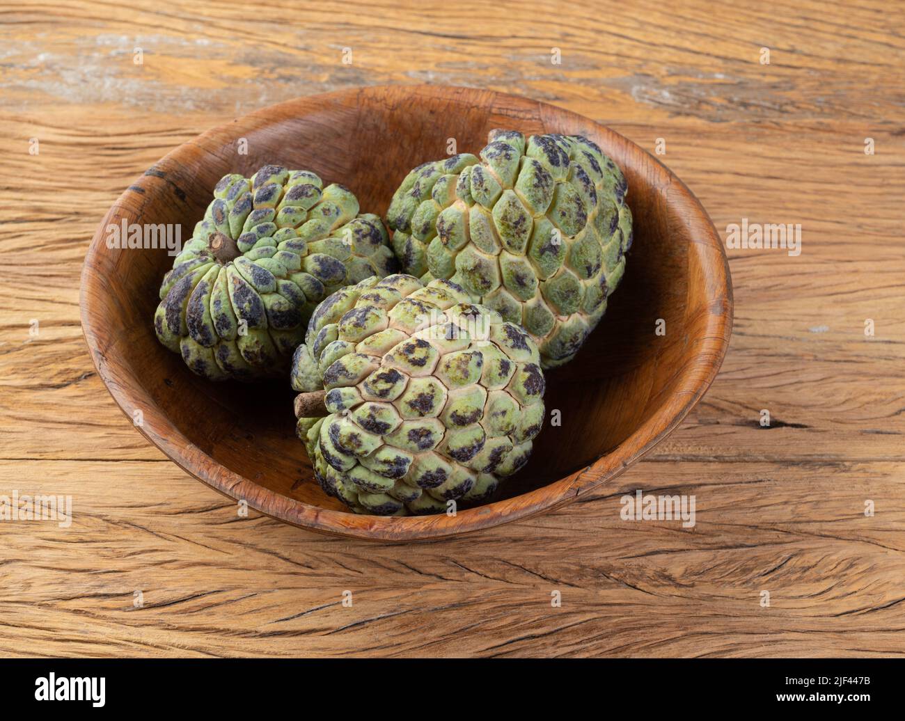 Sugar apples or custard apples in a bowl over wooden table. Stock Photo