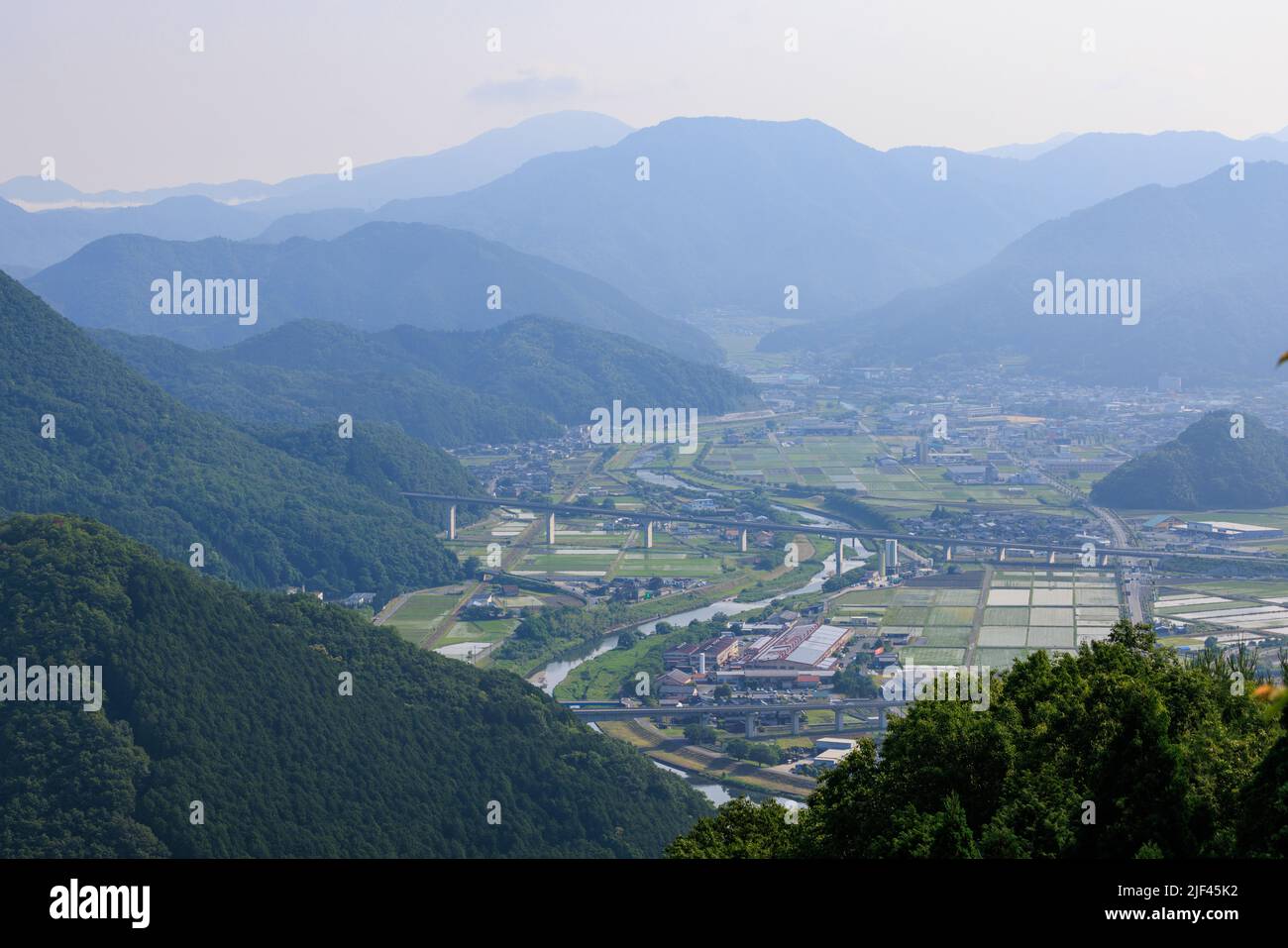 Winding river through small town in valley between blue mountains Stock Photo