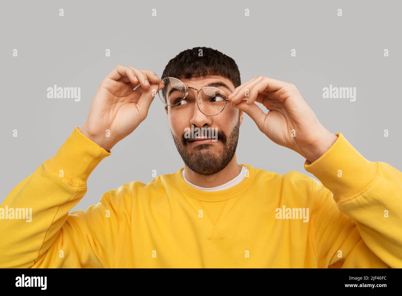 goofy young man in glasses and yellow sweatshirt Stock Photo