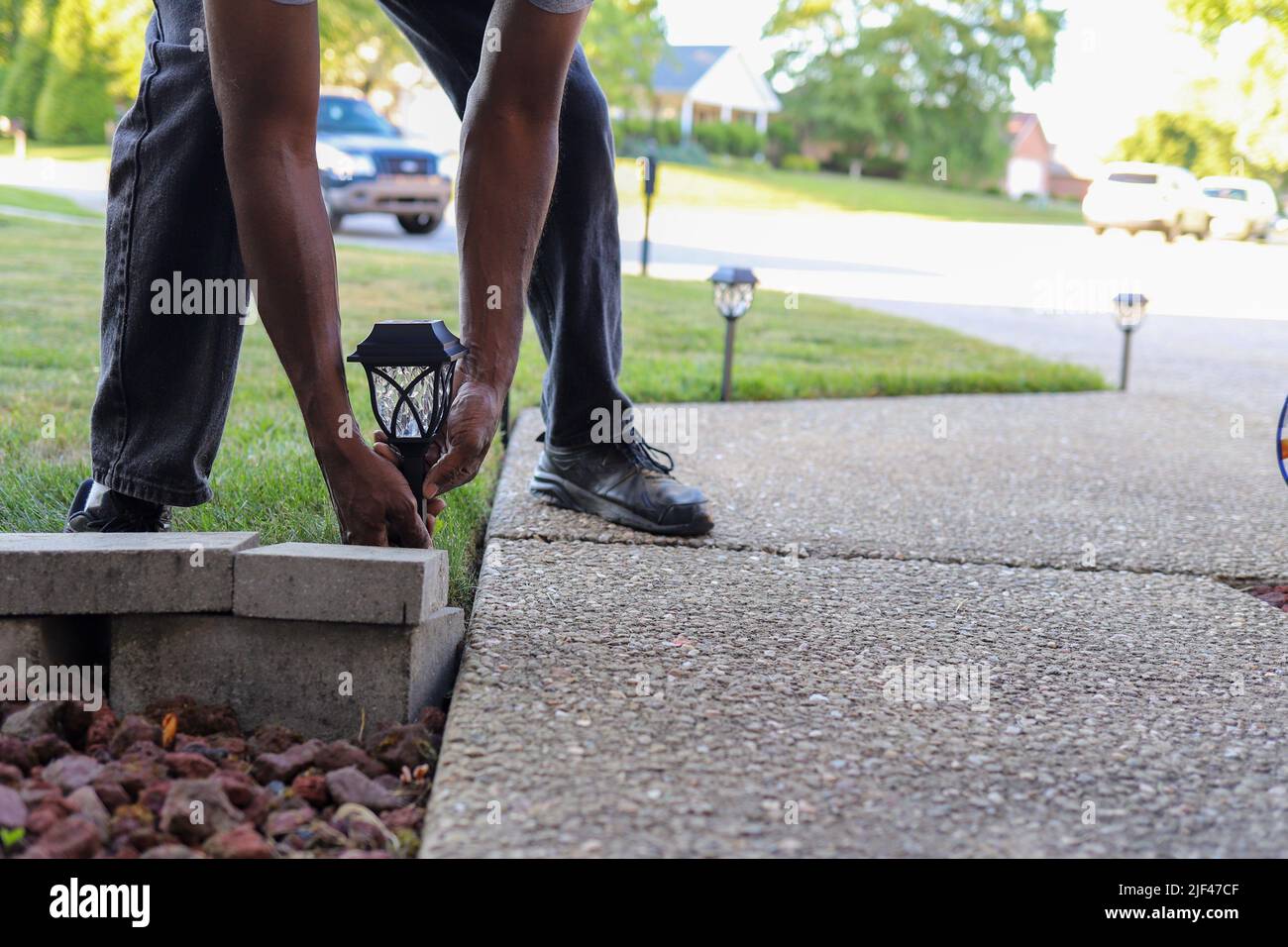 A black African-American man installing a solar  landscaping light in a lawn Stock Photo
