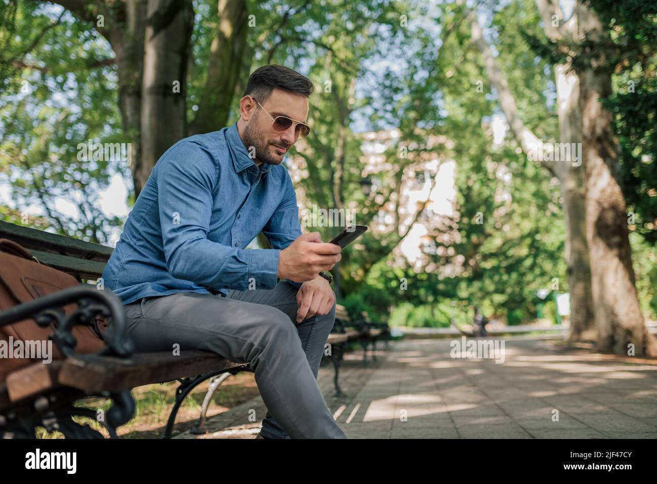 Young businessman text messaging on smart phone. Confident male ...